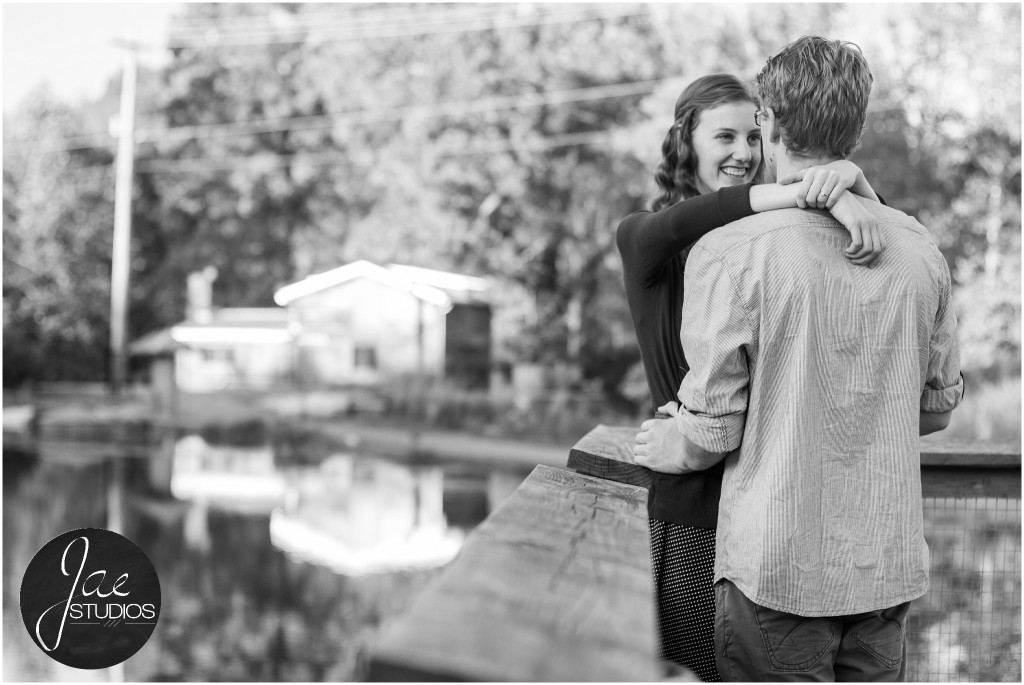 Lynchburg Engagement Patrick and Rebecca. Smiling while hugging each other in front of a lake with a house in the background.