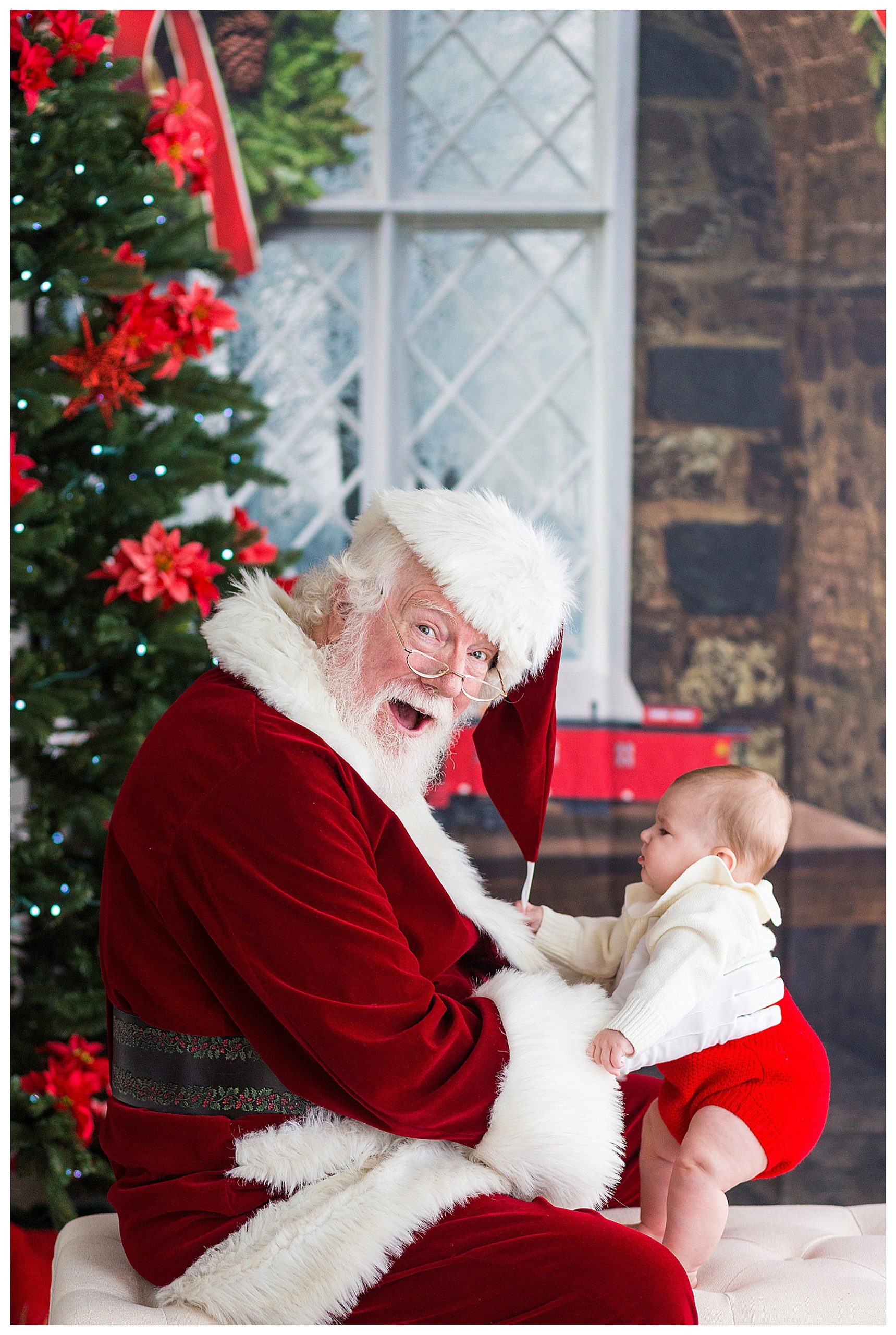 Santa holding a baby and looking at the camera with a shocked expression.